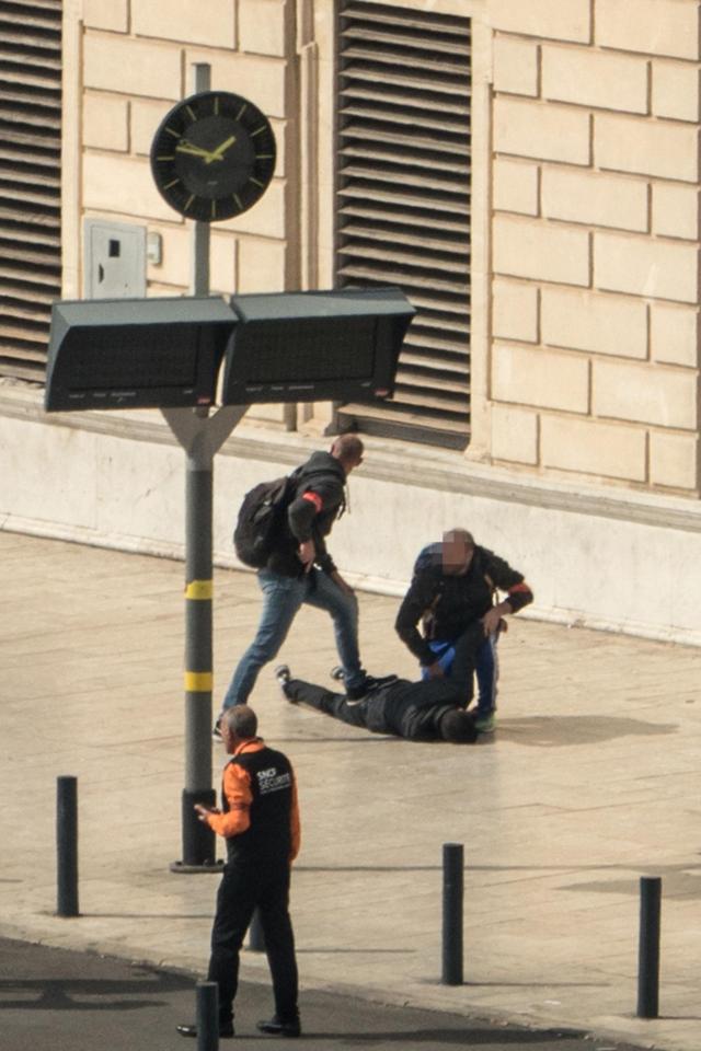  French policemen turn over and hold the knife attacker, a known criminal who is believed to be in his 30s