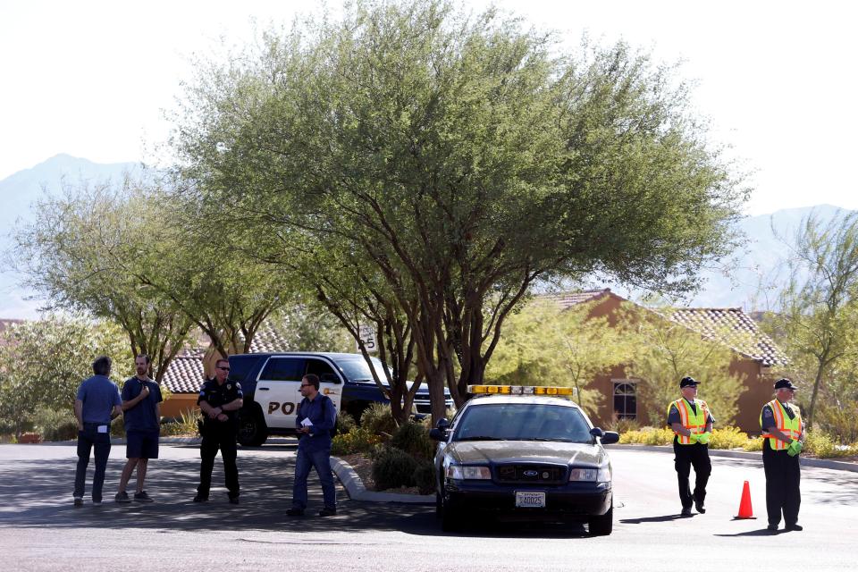  Cops stand guard to the entrance of the quiet community where he lived