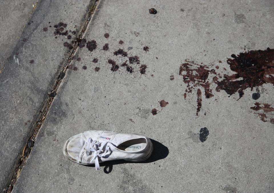  The blood of one of the victims is splattered on the ground next to a shoe