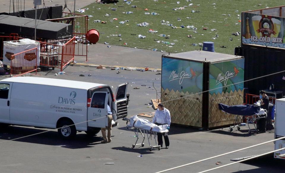  Workers are seen loading a corpse in a body bag into the back of a van today