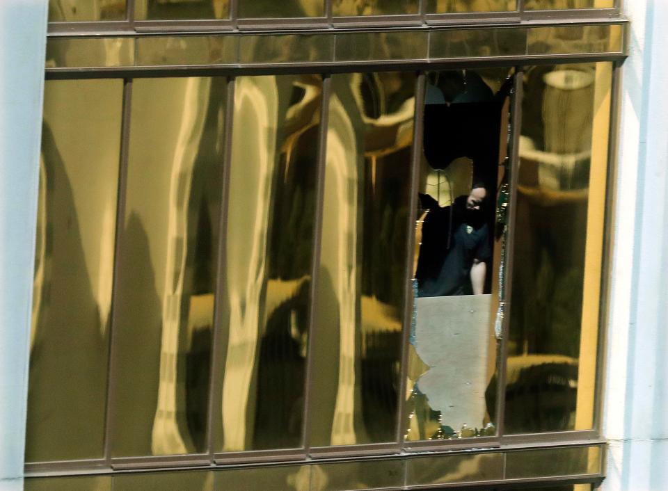  An investigator can be seen examining the room through a broken window