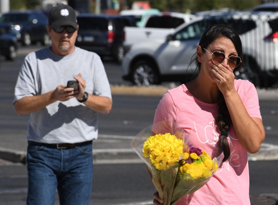 A survivor brings flowers to the makeshift shrine to those who were killed 