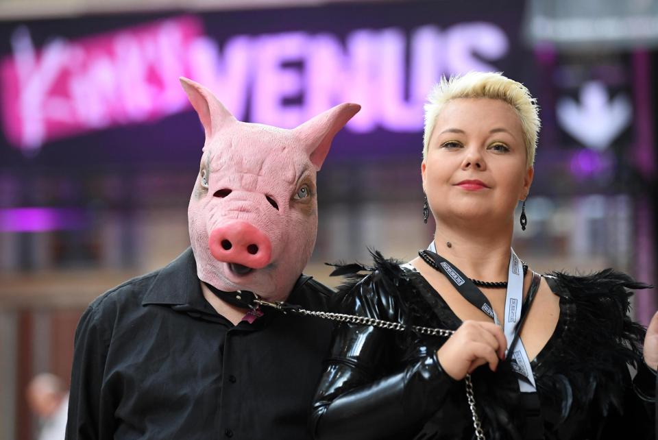  A woman leads a pal wearing a pig's mask through the event