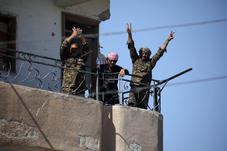  SDF fighters flash V for victory signs from a balcony in Raqqa