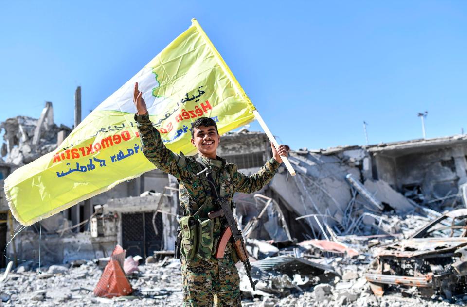  A member of the Syrian Democratic Forces holds up the militia's flag at the iconic Al-Naim square in Raqqa