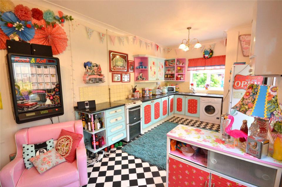 The kitchen is in the style of an American roadside diner with pink and blue walls, chequered flooring, and a Rock'N'Roll jukebox