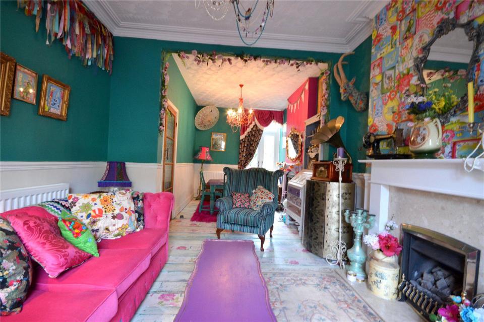 The furnishings in the front room have a mismatch of different patterns while the walls are a deep teal colour