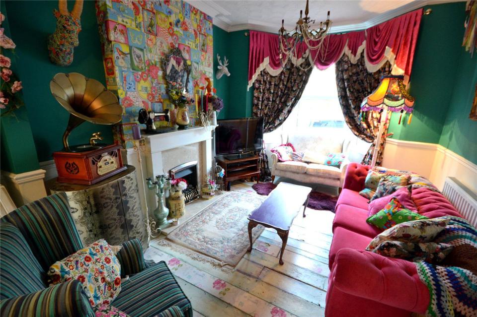 The living room has been decorated with a vivid print on the chimney breast while the ornaments include a gramophone and a colourful stag's head