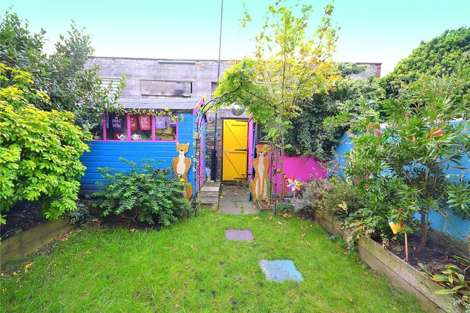 Even the garden shed has been painted in bold blues, pinks and yellows, while two cut out leopards guard the back gate