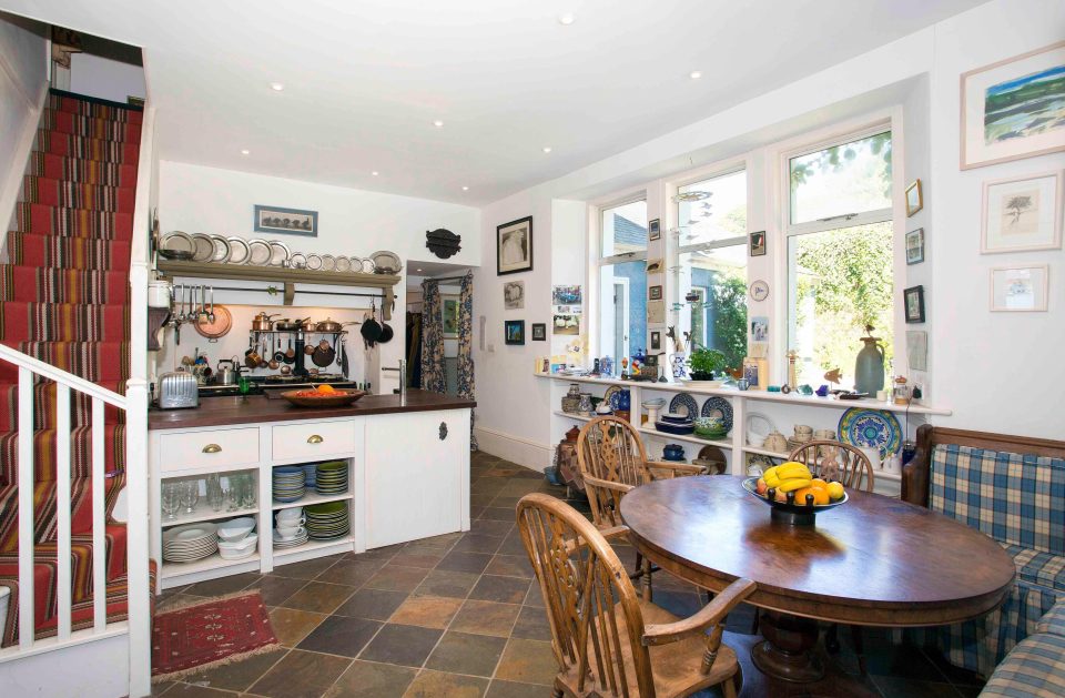 The kitchen is bright and spacious with a large breakfast seating area and stairs leading to the first floor