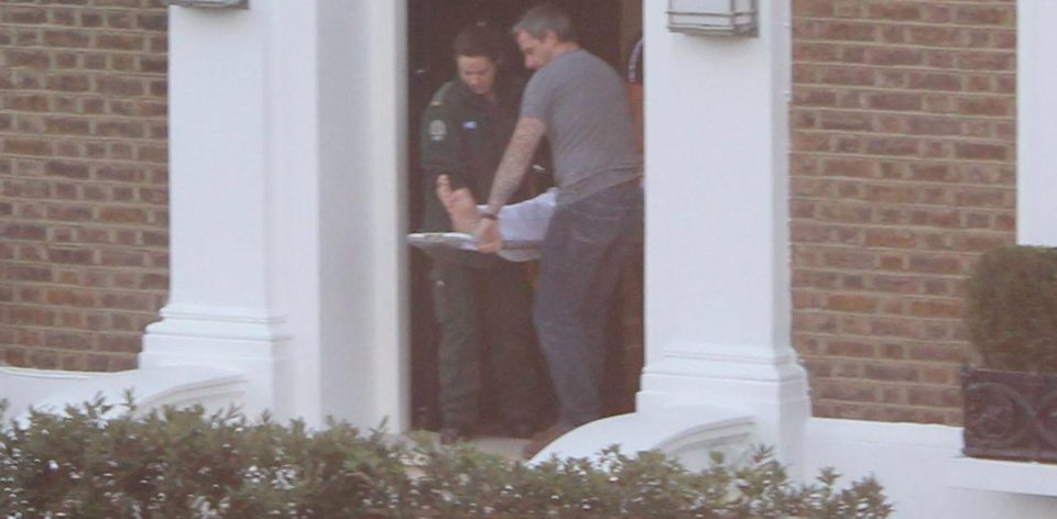  Ambulance medics help carry the music mogul out of his plush London house