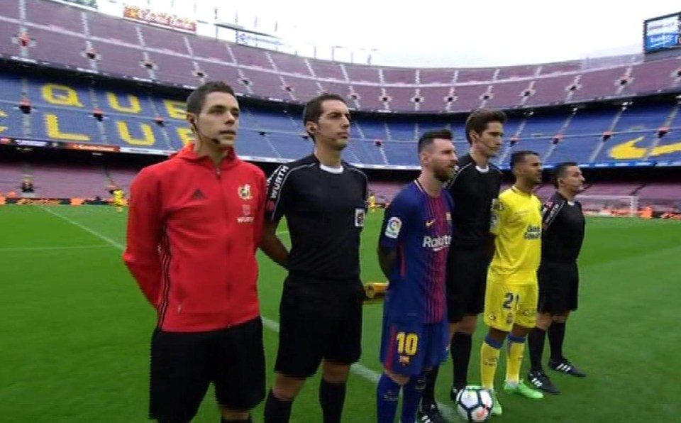 Lionel Messi stands with the match officials in front of an empty Nou Camp