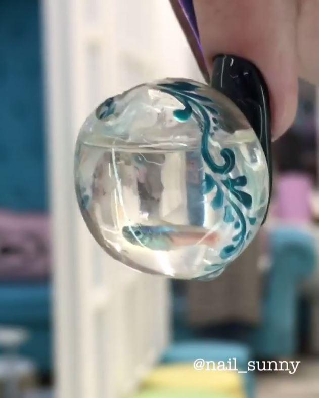 The manicure features a handmade mini fish tank attached to the nail - complete with a live fish