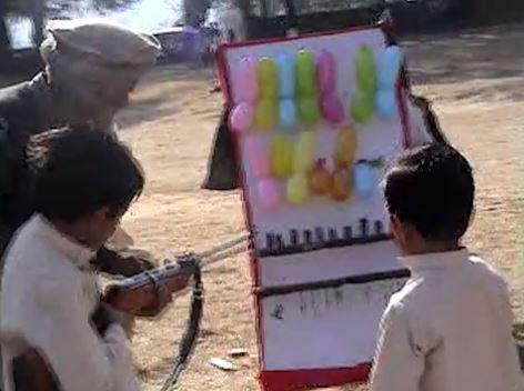  Two children are taught how to shoot a gun at water balloons inside the Osama bin Laden compound