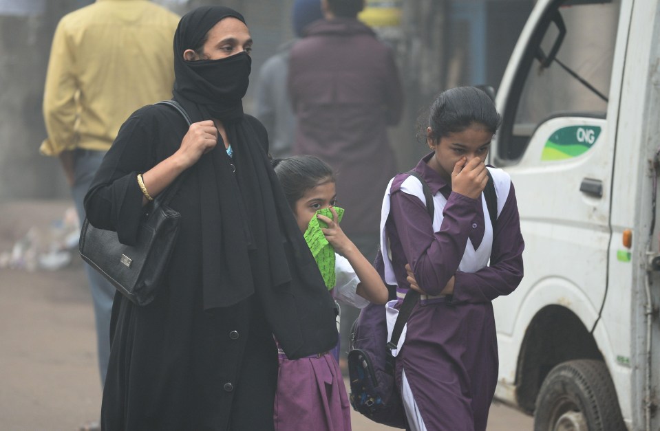 Residents make their way through the city while covering their faces