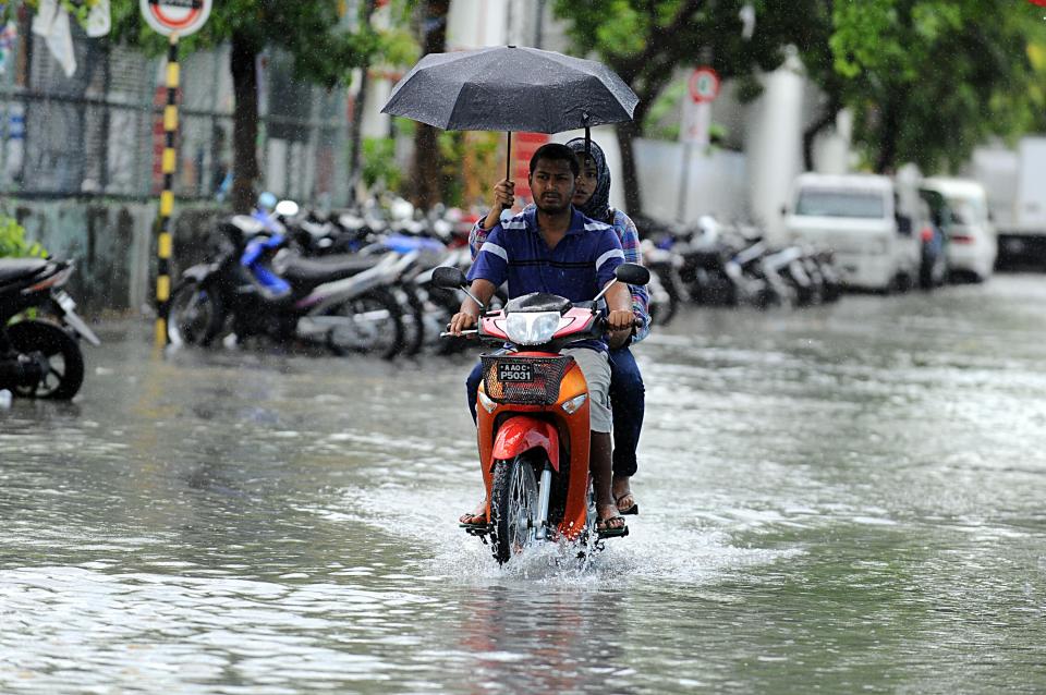  A man drives along a flooded street in Male, the Maldives, during a 2013 flood