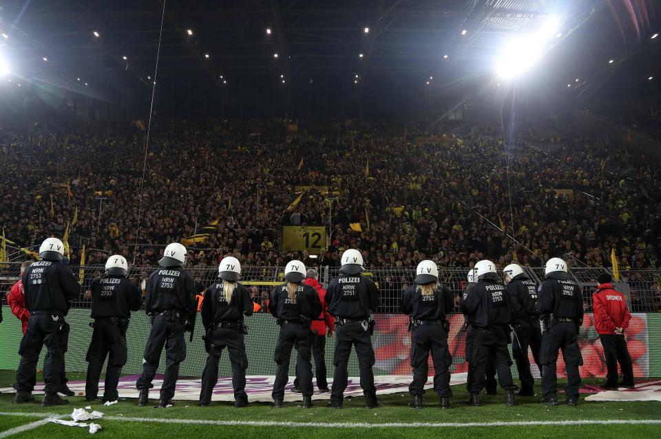  Police and security officials try and restrain Dortmund supporters