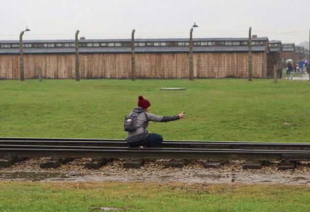  A girl crouches down to take a selfie on the train tracks that were used to ship hundreds of thousands to their deaths on the site in Oswiecim, Poland