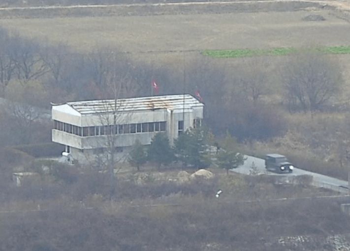  The jeep races past a guard post flying the North Korean flag