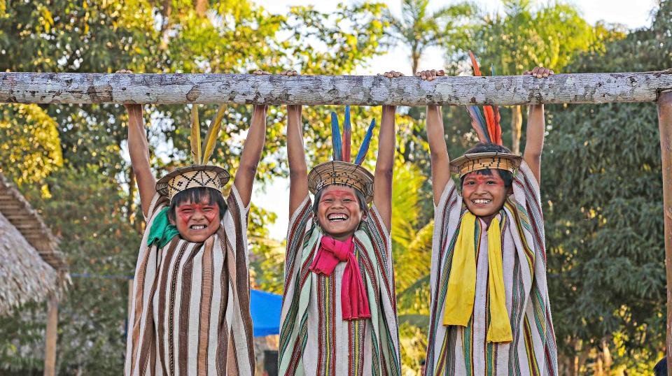  The same smiling Ashaninka children hang on to a wooden bar as they play in Apiwtxa village