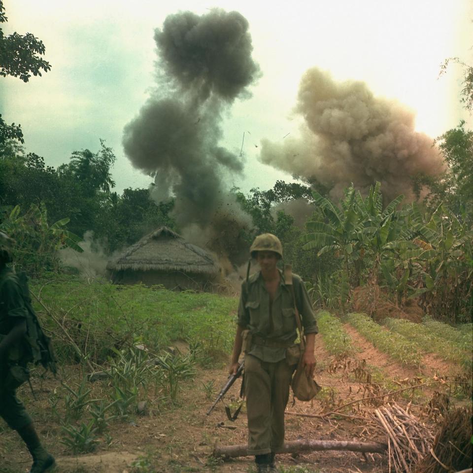  US Marines walk away from blown up bunkers and tunnels used by the Viet Cong