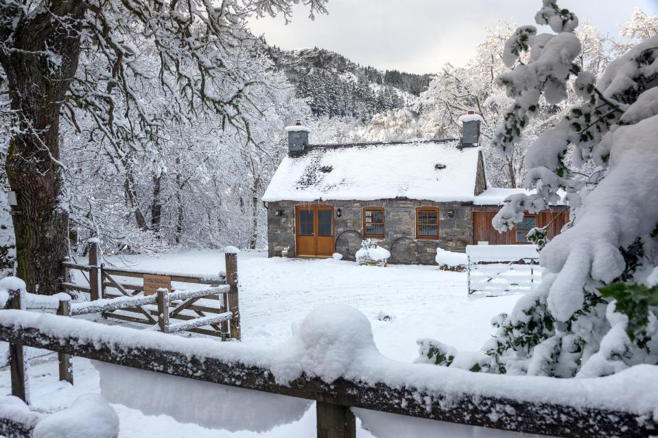  A picturesque snowy scene of a Scottish cottage nestled in the highlands