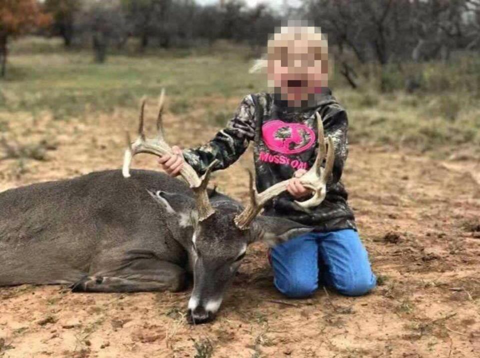  A blood-spattered young girl poses with a slaughtered deer for Kendall Jones's Cute Little Hunter contest