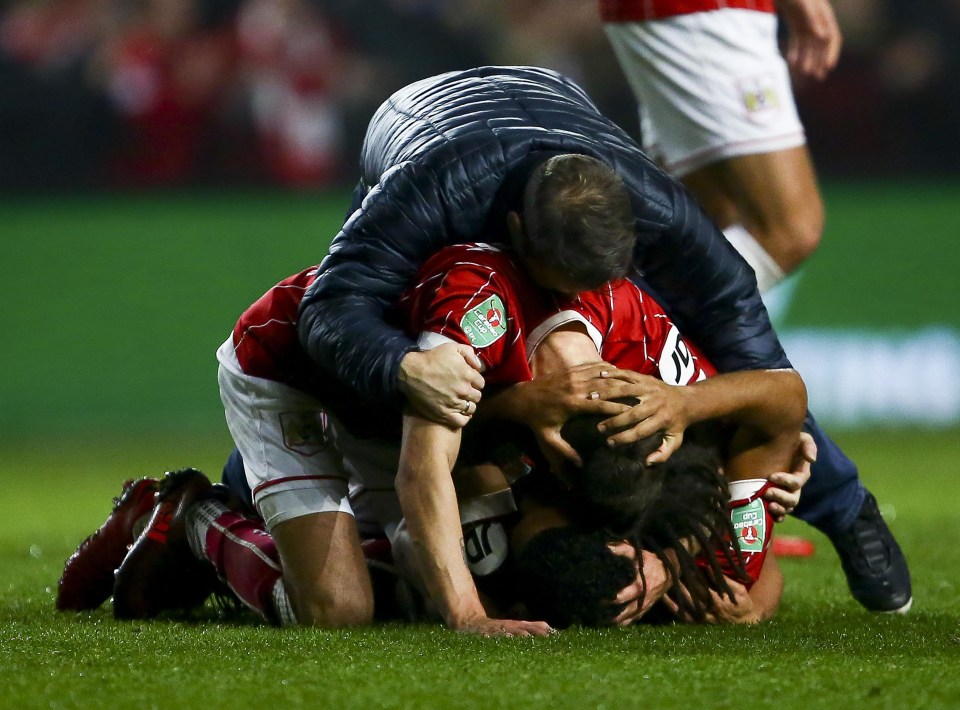 Bristol City players are jumped on by fans after securing an historic win over Manchester United