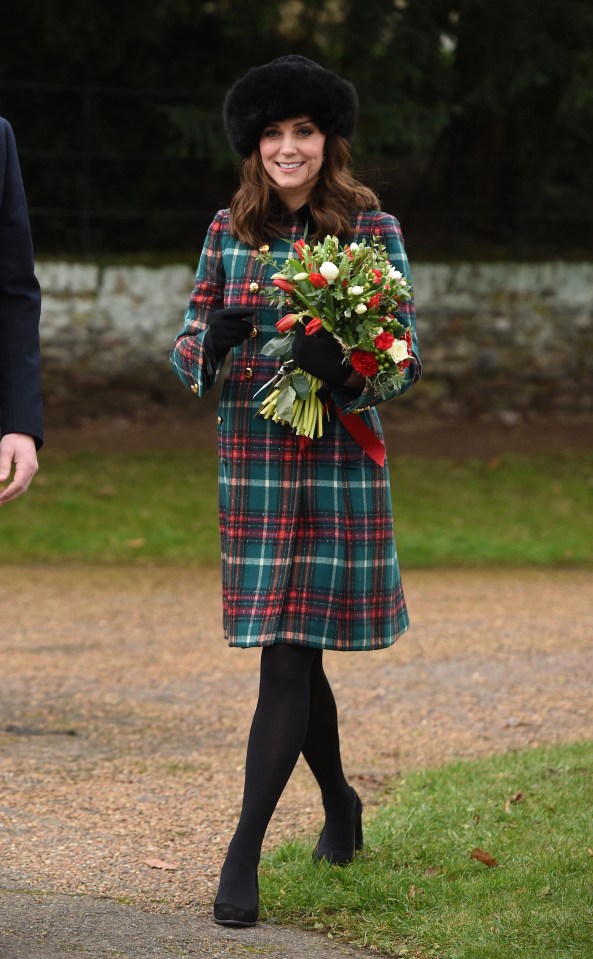 A smiling Kate Middleton carries a bouquet of flowers at Sandringham