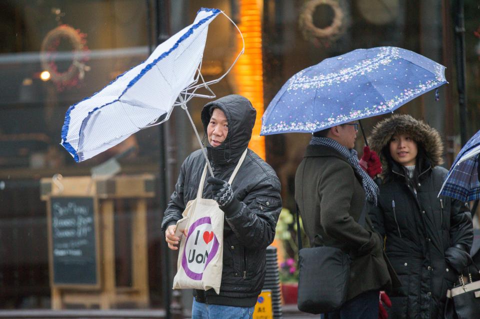  This man doesn't seem to be having much luck with his umbrella as he strolls through Cambridge