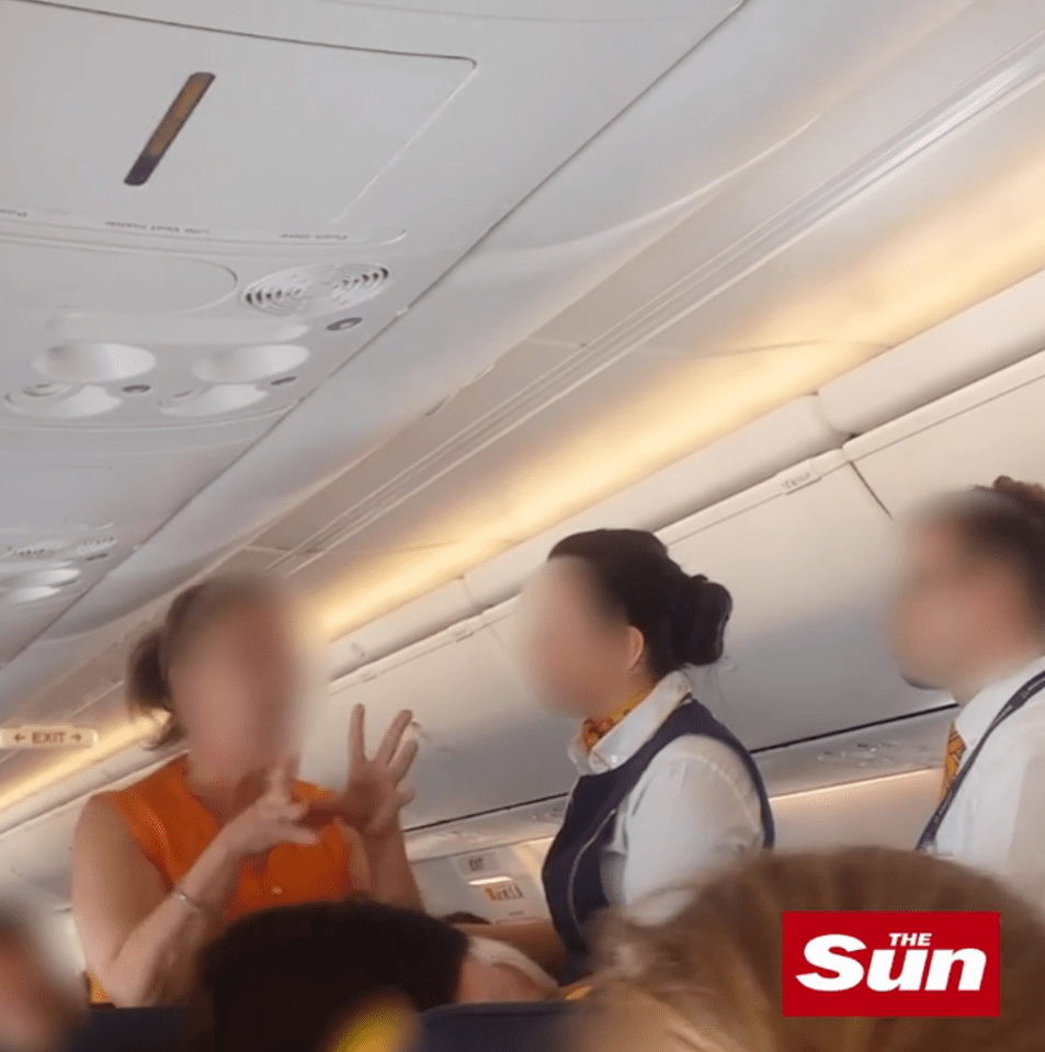  An air stewardess can be seen trying to calm the woman down