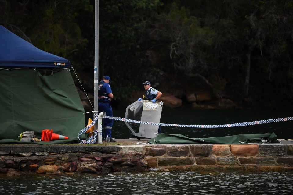 An officer carries a piece of debris recovered from a seaplane that crashed into the Hawkesbury River