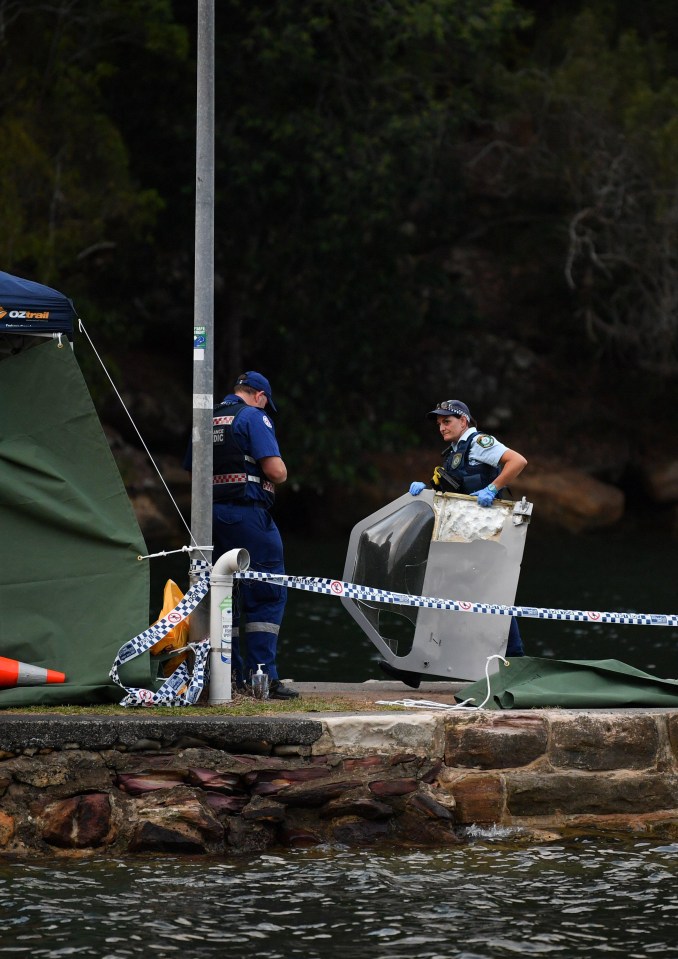 An officer carries a bit of debris from the crash site