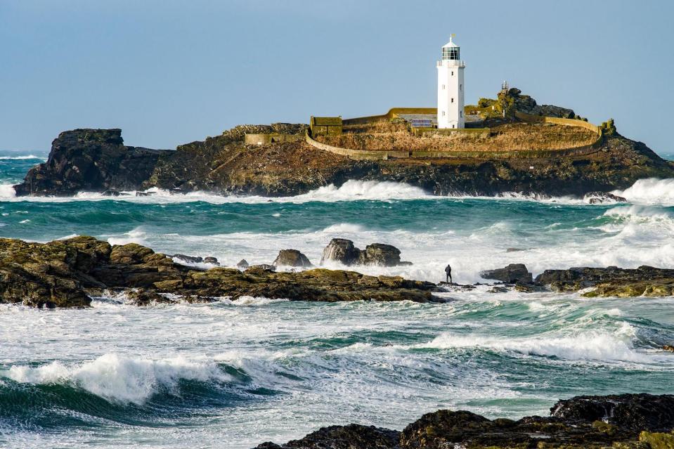  A man was pictured standing on rocks surrounded by dangerous waves at Godrevy Lighthouse near St Ives in Cornwall during high winds yesterday