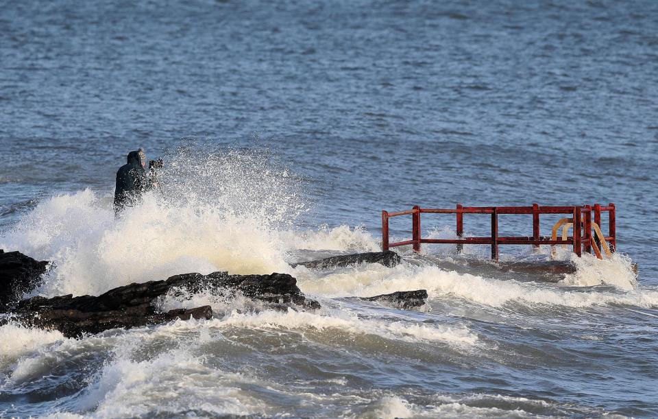  A man taking photographs gets caught by crashing waves at High Rock in Portmarnock, Dublin