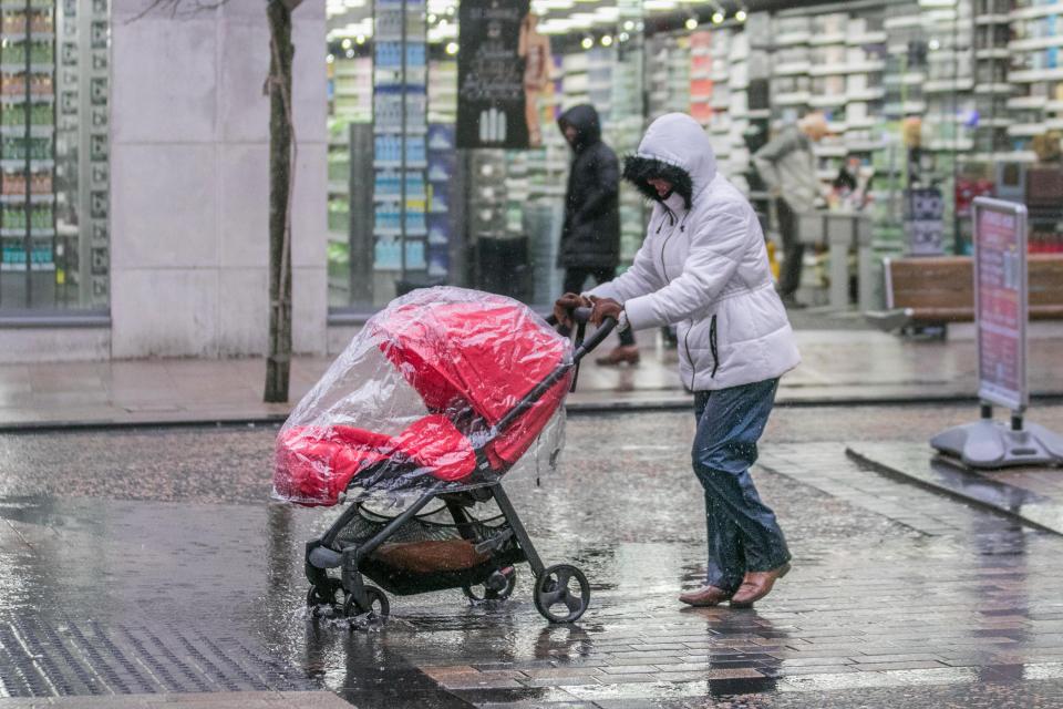  Heavy rain in Preston as a woman makes her way down the high street with a pram