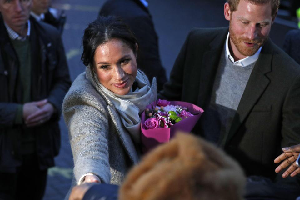  Meghan smiles as she is handed flowers from a fan