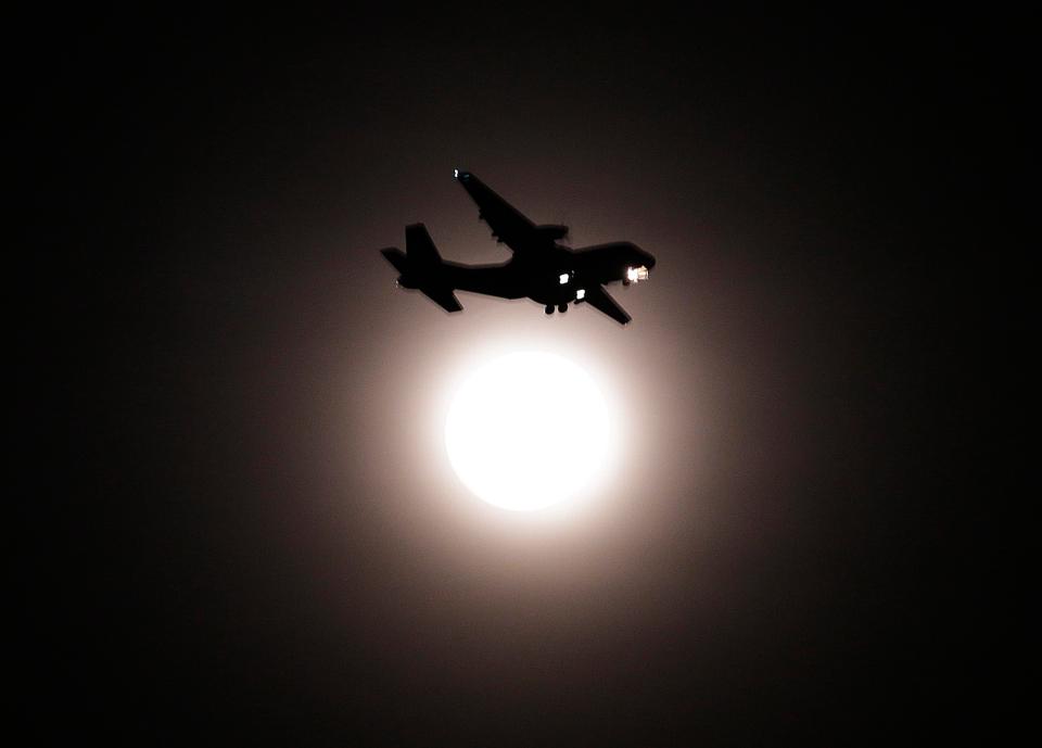  An airplane passes the full moon on its final approach before landing in Seoul