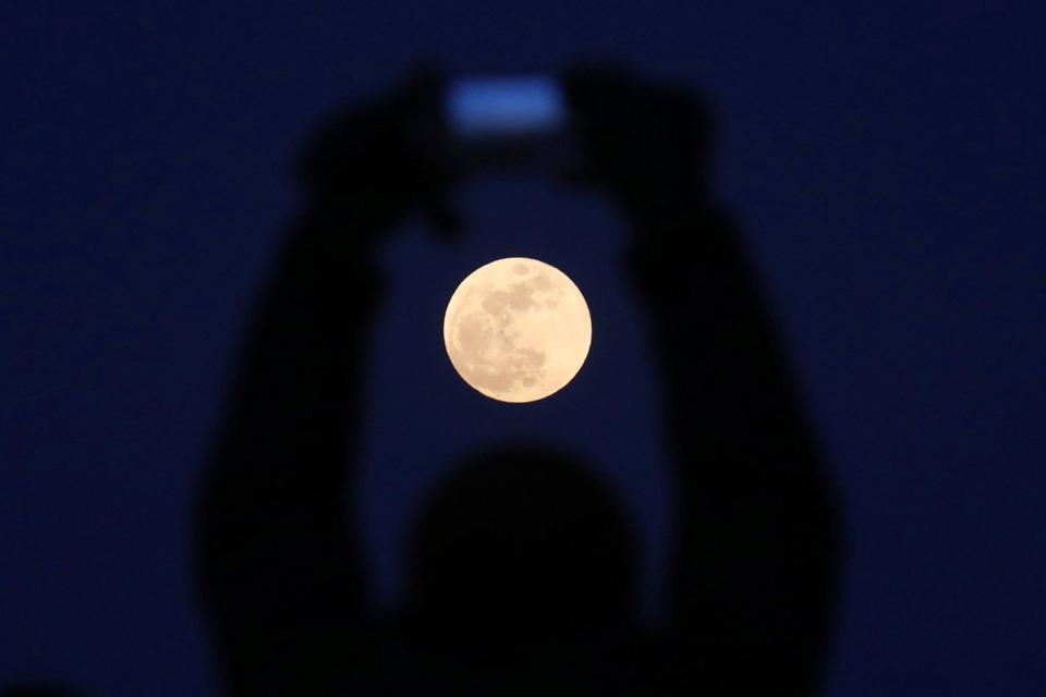  A Chinese man uses his camera to take photos as our satellite rises in Beijing