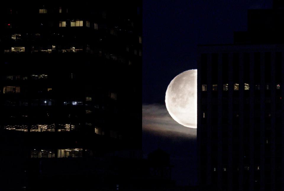  The moon sets behind high-rise buildings in New York city