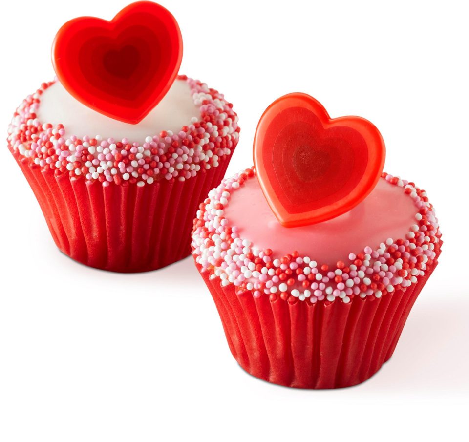  The cakes are hand decorated with red and white sugar sprinkles and finished with a plastic novelty heart shaped ring on top.