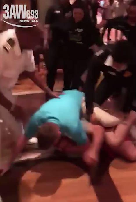 Two men fall onto the ground during the melee as security surrounds them