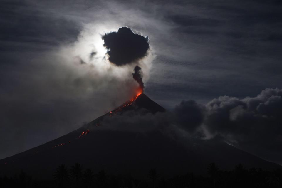  The 'super blue blood moon' obscured by clouds illuminates Mayon volcano as it spews ash near Legazpi City in the Philippines