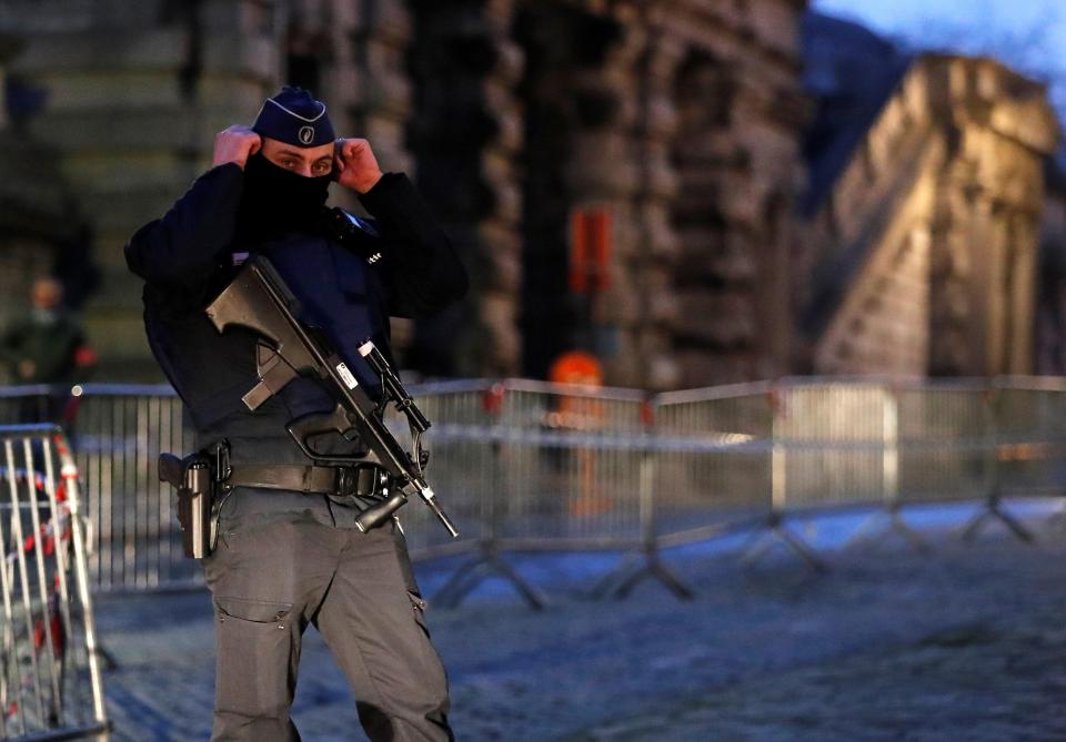 A heavily-armed Belgian police officer keeps guard at the entrance of the courthouse