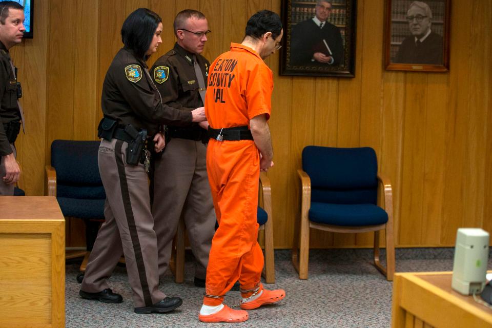 Nassar is escorted out of the courtroom by cops to begin his prison sentence 