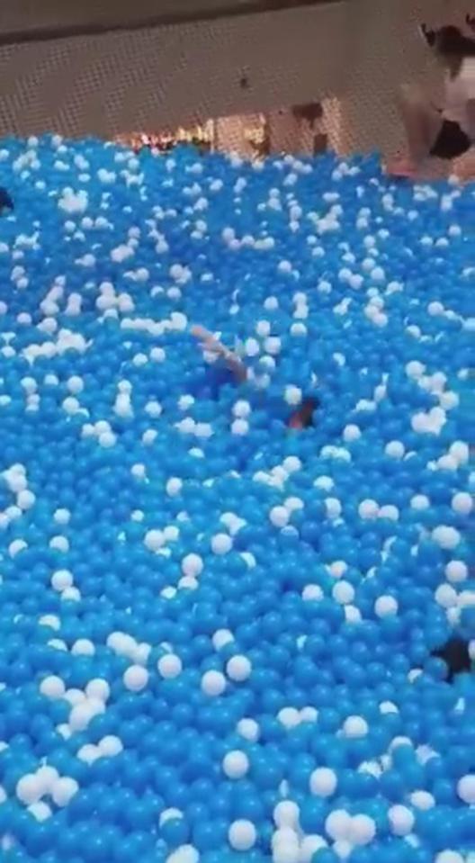  Vivien Low waves for help as she slips beneath a sea of 40,000 plastic balls