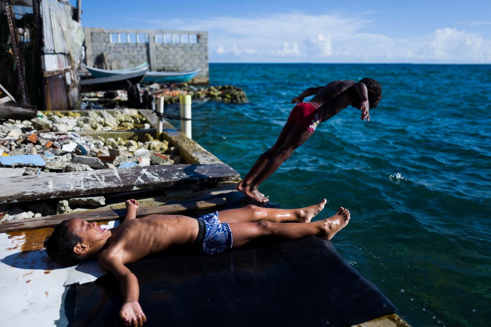 A child dives into the water to cool off as another lies on the island’s shore