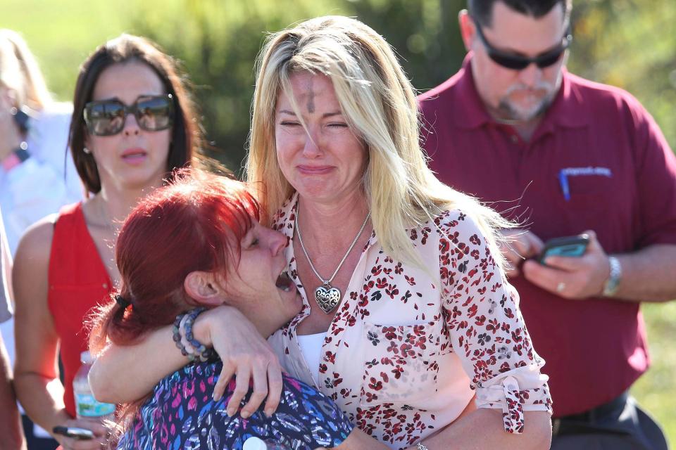  A woman fresh from an Ash Wednesday service embraces another with the sign of the cross still on her forehead