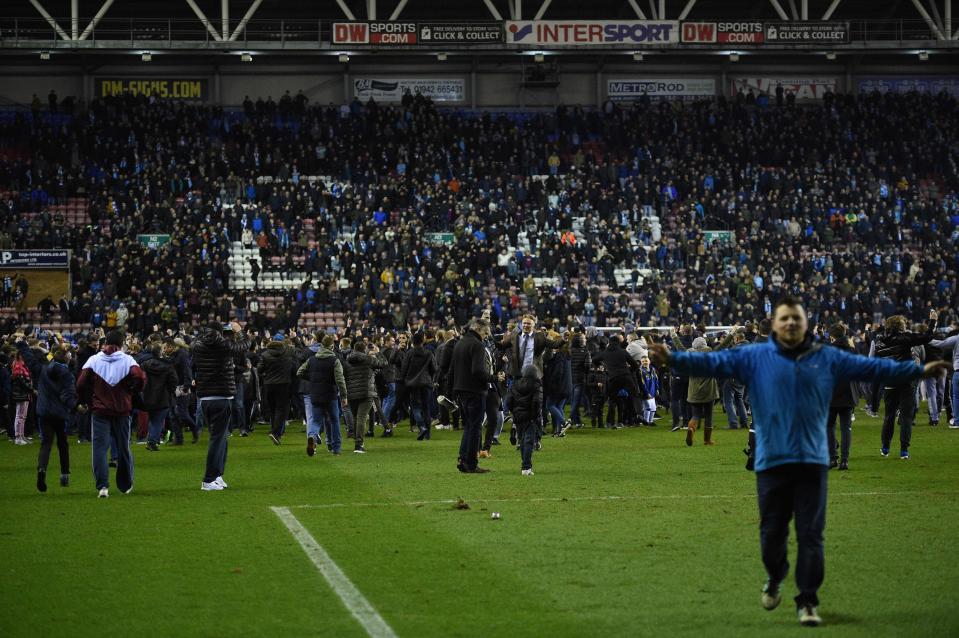  Wigan fans streamed onto the pitch to celebrate and taunt City fans