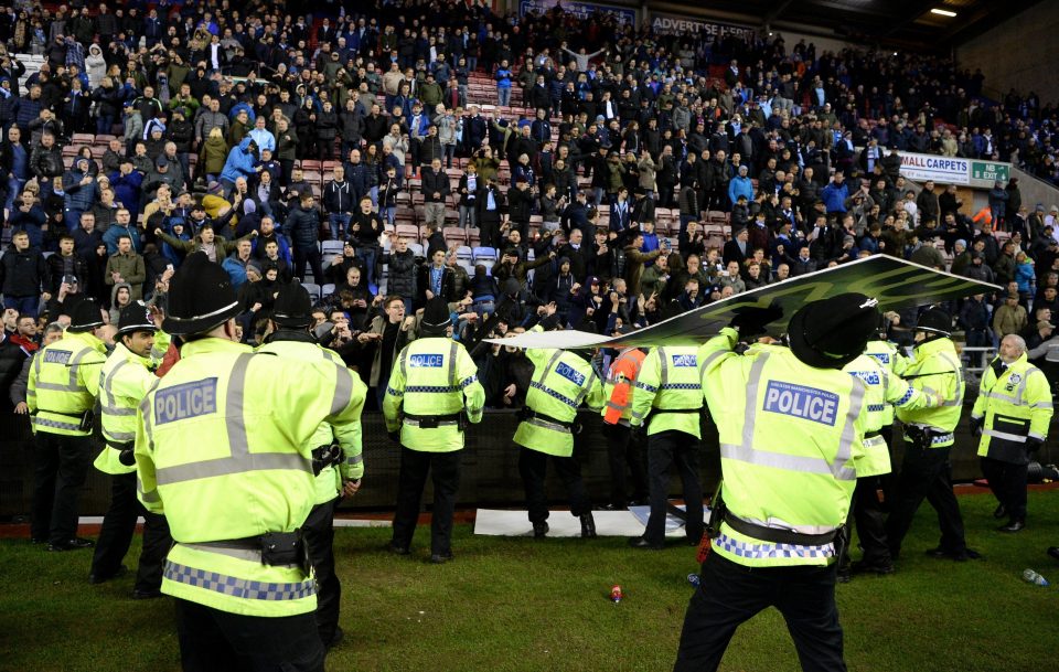  A police officer is struck by an advertising board thrown by City fans after their team were dumped out of the FA Cup